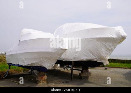 Bateau à moteur à l'eau garée protégé par un film plastique pour l'hivernage de nouveaux bateaux dans un enveloppe enveloppante enveloppante rétractable sur un voilier entreposé pour l'hiver Banque D'Images