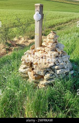 Signe du Camino de Santiago avec coquille de pétoncle accrochée sur le poteau sur une pile de pierres Banque D'Images