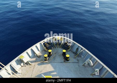 Vue sur la mer Méditerranée bleu calme et station d'amarrage avec des bollards jaunes, des rouleaux d'amarrage et un arc de panama sur une avant de navire de conteneur de cargaison. Banque D'Images