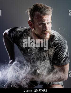 vue de face d'un joueur de rugby masculin sportif tenant le ballon avec de la poussière Banque D'Images