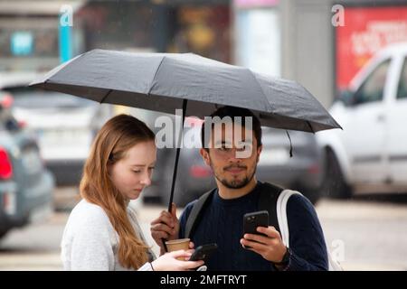 Les touristes recherchent l'emplacement avec le smartphone lors d'un jour de pluie dans les rues de Lisbonne Banque D'Images