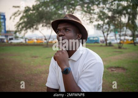 Portrait d'un jeune adulte africain avec une expression réfléchie dans un parc public Banque D'Images