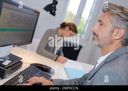 collègues joyeux qui examinent des épreuves sur ordinateur Banque D'Images