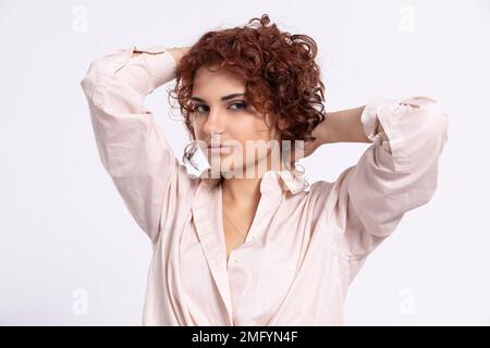 La fille corrige ses cheveux bouclés avec deux mains. Européen. Banque D'Images