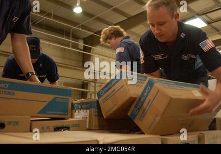 Personnel de la Garde côtière - fournitures - 26-HK-84-62. Personnel de CG avec fournitures -- membres de CG NSF soulevant des boîtes dans la zone de stockage, 050901i. Ouragan Katrina Banque D'Images