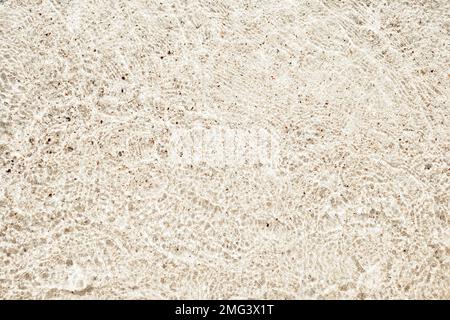 Texture de sable jaune, cailloux et eau claire. Magnifique plage arrière-plan. La texture sans couture. Banque D'Images
