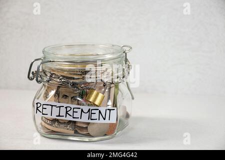 Pièces de monnaie et dollars dans un pot de retraite en verre avec une chaîne en métal et un cadenas Banque D'Images