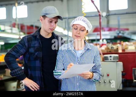 Une superviseure s'est entretenant avec un jeune contremaître de l'usine de tri des agrumes Banque D'Images