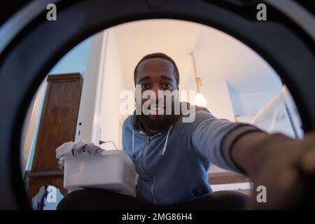 Un jeune garçon recueille les vêtements fraîchement lavés de la machine à laver, concept de travaux ménagers Banque D'Images