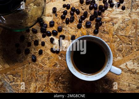 Une tasse de café Java et de grains de café sur une table rustique en bois Banque D'Images