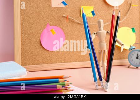 Mannequin en bois avec crayons colorés sur la table, gros plan Banque D'Images