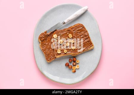 Assiette de délicieux toasts au beurre de noisette et aux noix sur fond rose Banque D'Images