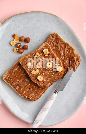 Assiette de toasts savoureux avec beurre de noisette et noix sur fond rose, gros plan Banque D'Images