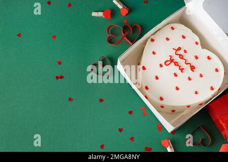 Gâteau à bento en forme de cœur dans une boîte et coeurs sur fond vert. Célébration de la Saint-Valentin Banque D'Images
