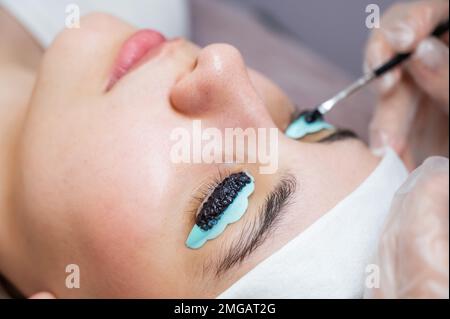 Gros plan portrait d'une femme sur la procédure de lamination des cils. Le maître applique la teinte aux cils. Banque D'Images