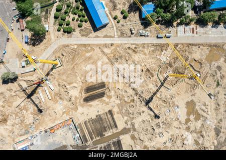 vue aérienne du site préparée pour la construction avec des grues et des matériaux de construction empilés Banque D'Images