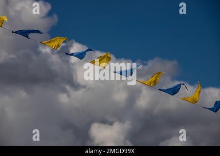 Drapeaux triangulaires jaune et bleu sur fond de ciel avec nuages blancs. Fête en plein air. Ambiance festive Banque D'Images