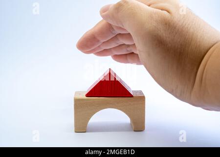 Maison modèle en bois couverte par la main de l'homme pour la protection. Assurance de biens, concept d'investissement immobilier. Banque D'Images