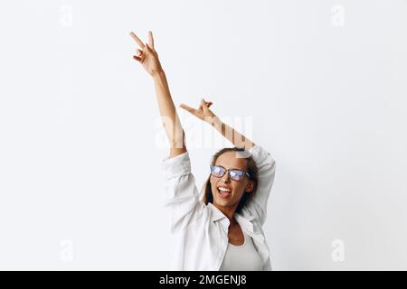 Portrait de femme avec peau bronzée portant des lunettes de vue sur un fond blanc souriant avec les dents et les mains en haut dans la joie Banque D'Images