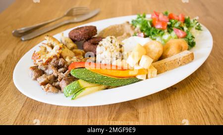 Assiette combinée africaine avec riz, fromage frit, légumes grillés, sauce aux arachides et autres produits traditionnels. Banque D'Images