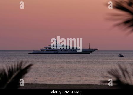 IOS, Grèce - 3 juin 2021 : vue sur un yacht de luxe à la célèbre plage de Mylopotas à iOS Grèce et un coucher de soleil violet Banque D'Images