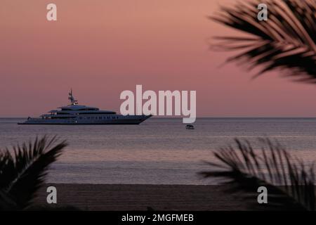 IOS, Grèce - 3 juin 2021 : vue sur un yacht de luxe à la célèbre plage de Mylopotas à iOS Grèce et un coucher de soleil violet Banque D'Images