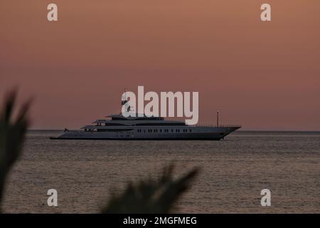 IOS, Grèce - 3 juin 2021 : vue sur un yacht de luxe à la célèbre plage de Mylopotas à iOS Grèce et un coucher de soleil violet Banque D'Images