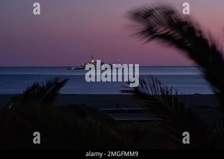 IOS, Grèce - 3 juin 2021 : vue sur un yacht de luxe à la célèbre plage de Mylopotas à iOS Grèce et un coucher de soleil violet Banque D'Images