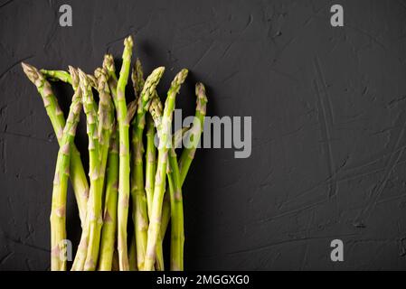 Tiges d'asperges crues. Arrière-plan sombre. Placer pour le texte. Banque D'Images