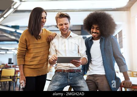 La relation de travail a été excellente. trois jeunes gens d'affaires qui regardent une tablette dans leur bureau. Banque D'Images