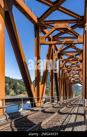 Pont de transport ferroviaire en treillis métallique étroit rouillé traversant la rivière Columbia dans la réserve nationale de la gorge de la rivière Columbia du Nord-Ouest avec un seul train ferroviaire Banque D'Images