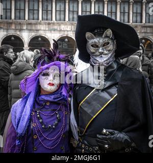 Couple d'âge moyen - femme en costume de carnaval violet, homme en costume de bottes - au carnaval à Venise, Italie. Banque D'Images