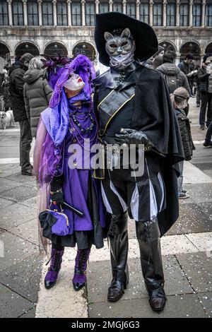 Couple d'âge moyen - femme en costume de carnaval violet, homme en costume de bottes - au carnaval à Venise, Italie. Banque D'Images