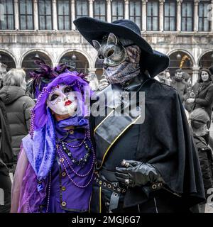 Couple d'âge moyen - femme en costume de carnaval violet, homme en costume de bottes - au carnaval à Venise, Italie. Banque D'Images