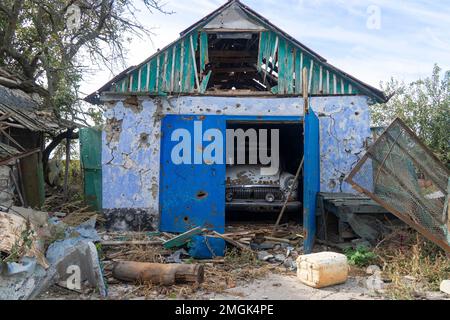 La voiture civile détruite est dans le garage. Sur la carrosserie de la voiture il y a des trous de balles et de éclats. Invasion russe de l'Ukraine Banque D'Images