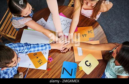 Unir les dirigeants de demain. Prise de vue en grand angle d'un groupe de jeunes enfants méconnus qui se joignent aux mains dans l'unité à l'école. Banque D'Images