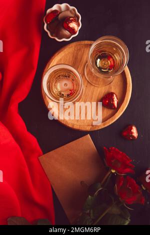 Dîner romantique de saison rouge avec carte postale, verres de champagne, roses rouges et bonbons au chocolat. Esthétique maquette de carte postale de la Saint-Valentin Banque D'Images