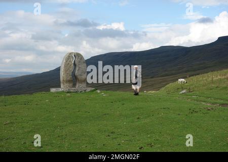 Man Walking to the Limestone 'Water Cut' Sculpture par Mary Bourne sur Mallerstang Common dans la vallée d'Eden, Yorkshire Dales National Park, Angleterre, Royaume-Uni Banque D'Images