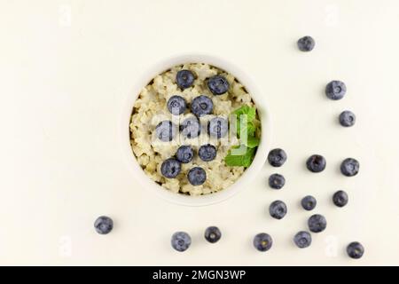 Bol pour porridge à l'avoine. Petit déjeuner sain céréales d'avoine avec bleuets, feuilles de menthe sur blanc Banque D'Images