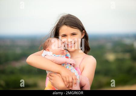 Jeune fille de 9 ou 10 ans tenant un bébé Banque D'Images