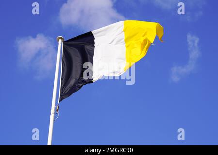 Drapeau de la ville d'Arcachon, au sud-ouest, agitant dans l'air sur un ciel bleu avec blanc noir jaune de couleur en France Banque D'Images