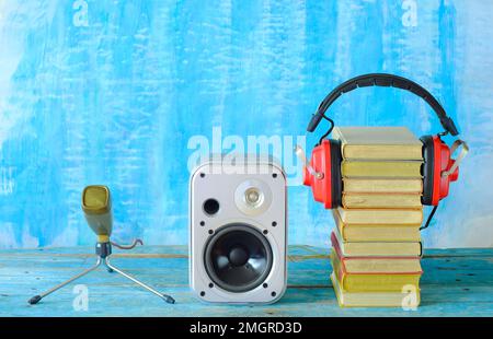 concept de livre audio avec pile de livres et écouteurs vintage, haut-parleur et microphone ancien, fond bleu, grundy, espace de copie gratuit Banque D'Images