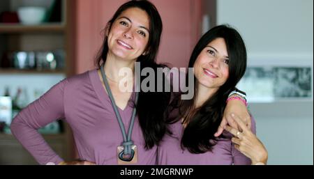 Les sœurs jumelles qui se posent ensemble deux femmes amis embrassent et aiment Banque D'Images