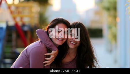 Deux sœurs adultes heureux posant ensemble à l'extérieur de frères et sœurs jumeaux avec les mêmes vêtements Banque D'Images