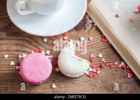 Macaron de lavande et d'amande avec un morceau de morsure sur fond de bois, avec de petits coeurs. Banque D'Images