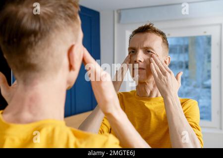 Adulte mature homme massant la crème à frotter le visage dans la peau Banque D'Images