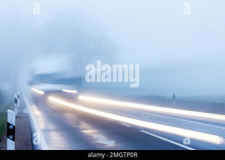 26 janvier 2023, Mecklembourg-Poméranie occidentale, Mühlen Eichsen : une fourgonnette traverse une avenue dans un brouillard dense. (Exposition longue) avec des températures autour de zéro degré, bruine et brouillard en partie dense, le temps d'hiver dans le nord de l'Allemagne montre son côté antipathique. Photo: Jens Büttner/dpa Banque D'Images