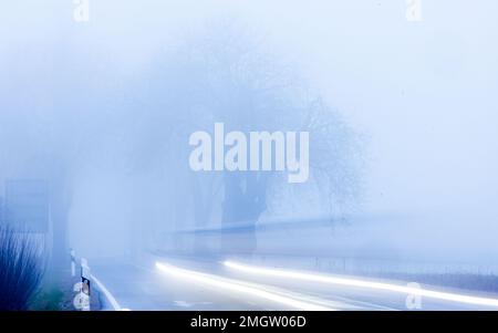 26 janvier 2023, Mecklembourg-Poméranie occidentale, Mühlen Eichsen : une fourgonnette traverse une avenue dans un brouillard dense. (Exposition longue) avec des températures autour de zéro degré, bruine et brouillard en partie dense, le temps d'hiver dans le nord de l'Allemagne montre son côté antipathique. Photo: Jens Büttner/dpa Banque D'Images