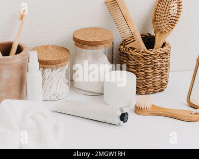 Bain arrière-plan vue avant avec boîte à paille, contenant avec brosses à dents, cosmétiques, bocaux et serviettes blanches sur fond blanc. Vue avant. Copier l'espace Banque D'Images