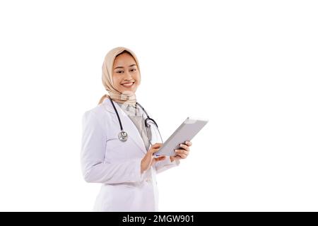 un médecin avec hijab souriant tout en portant la tablette à sa main Banque D'Images